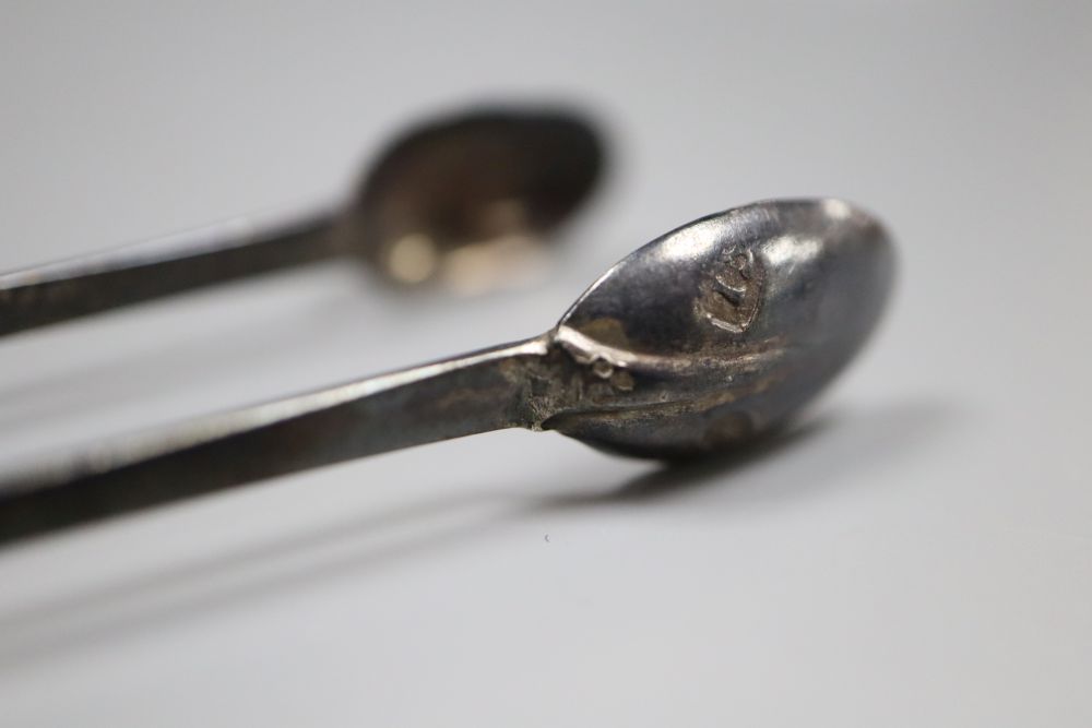 A pair of antique white metal sugar tongs in the form of fire tongs, indistinct marks, 12.4cm, 14 grams.